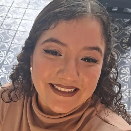 Samantha Gutiérrez - Mujer sonriente con cabello largo y rizado y blusa rosa.